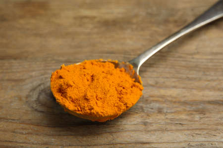 Spoon with saffron powder on wooden table, closeup