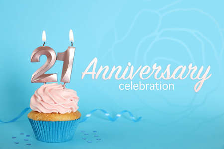 Delicious cupcake with number shaped candles on light blue background. Coming of age party - 21th birthday. Anniversary celebrationの写真素材