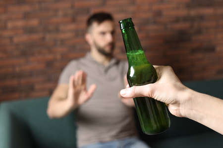 Man refusing to drink beer indoors, closeup. Alcohol treatment addictionの写真素材