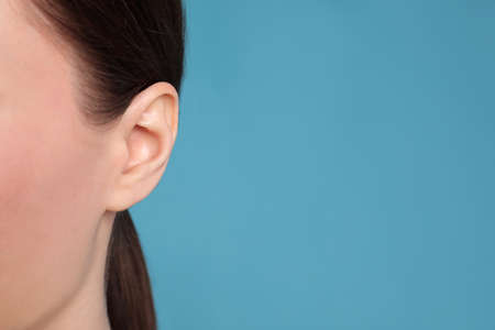 Woman on light blue background, closeup of ear. Space for textの写真素材