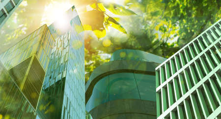 Go green concept. Low angle view of modern building and tree on sunny dayの写真素材