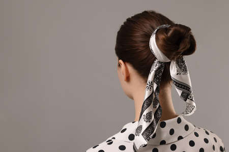 Woman with stylish bandana on light gray background, back view. Space for text