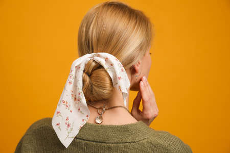 Young woman with stylish bandana on yellow background, back viewの写真素材