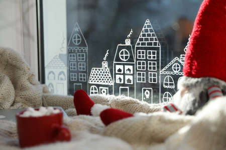 Gnome, laptop and hot drink on knitted plaid near window with beautiful drawing at home. christmas decorの写真素材