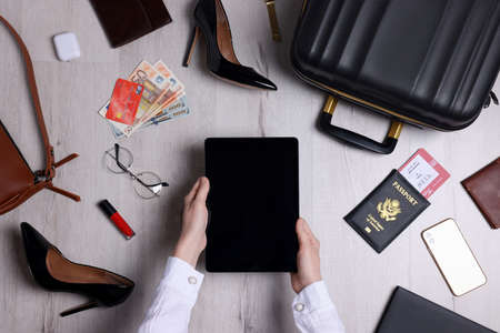 Woman preparing essentials for business trip on wooden floor, top viewの写真素材