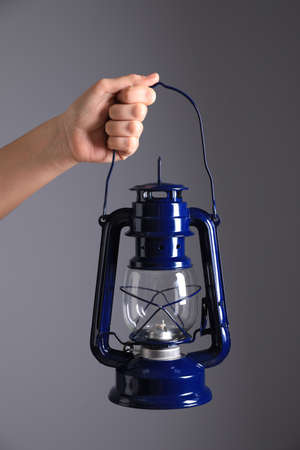 Woman holding blue kerosene lamp on gray background, closeupの写真素材