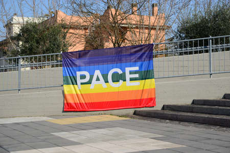 Beautiful rainbow peace flag with word PACE hanging on metal railing outdoorsの写真素材