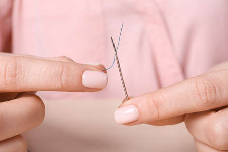 Woman threading sewing needle at table, closeupの写真素材