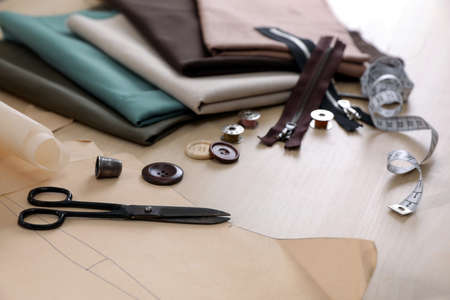 Set of sewing supplies and accessories with fabric on wooden table