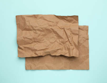 Sheets of crumpled brown paper on light blue background, top viewの写真素材