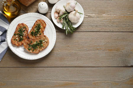 Tasty bruschettas with oil and garlic on wooden table, flat lay. Space for textの写真素材