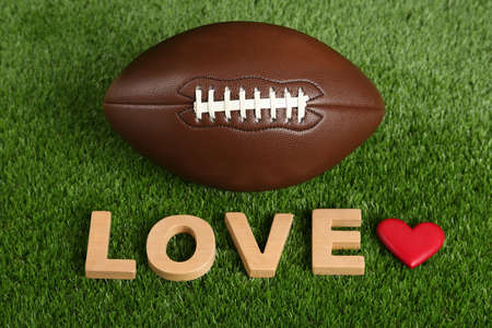 American football ball, word Love and heart on green grassの写真素材