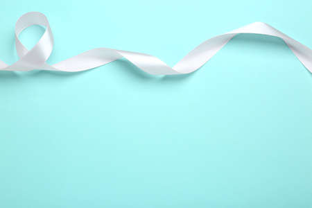 Beautiful white ribbon on light blue background, top view. Space for textの写真素材