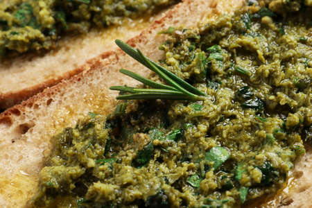 Tasty bruschetta with pesto and rosemary, closeup