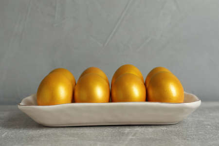 Shiny golden eggs on light gray tableの写真素材