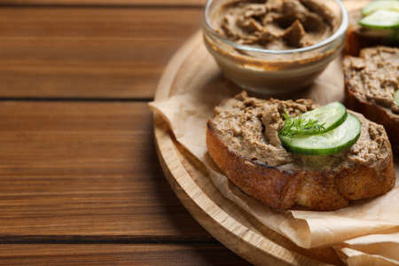 Slices of bread with delicious pate, cucumber and dill on wooden table, closeup. Space for text