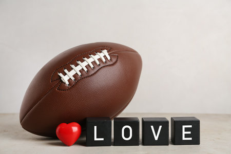 American football ball, cubes with word Love and heart on light gray table against white backgroundの写真素材