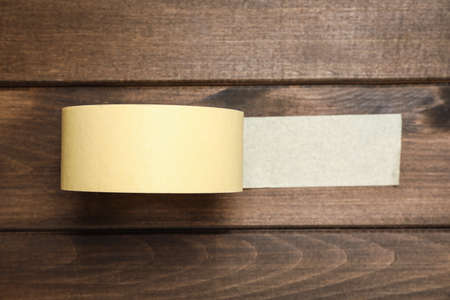 Roll of yellow adhesive tape on wooden background, top viewの写真素材