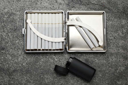 Open case with tobacco filter cigarettes and lighter on gray table, flat layの写真素材