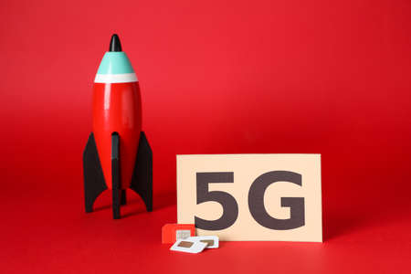 internet concept. Paper with phrase 5G, toy rocket and SIM cards on red backgroundの写真素材