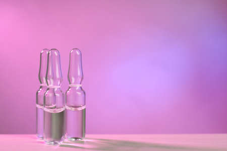 Pharmaceutical ampoules with medication on table against color background. Space for textの写真素材