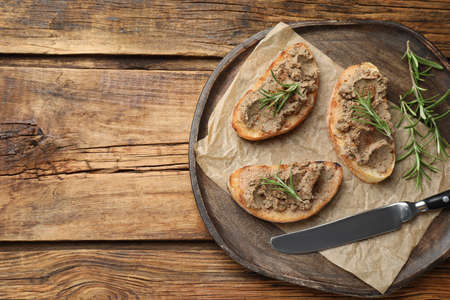 Slices of bread with delicious pate and rosemary on wooden table, top view. Space for textの写真素材