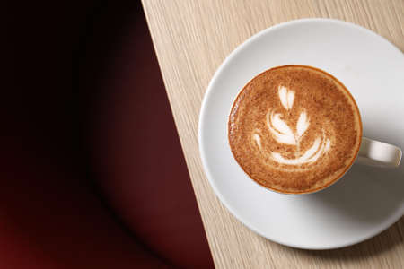 Cup of aromatic coffee on wooden table in cafe, top view. Space for text