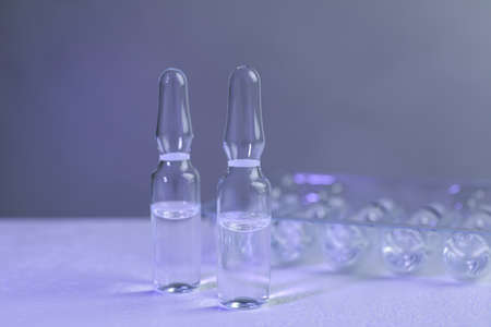 Pharmaceutical ampoules with medication on white table against gray backgroundの写真素材