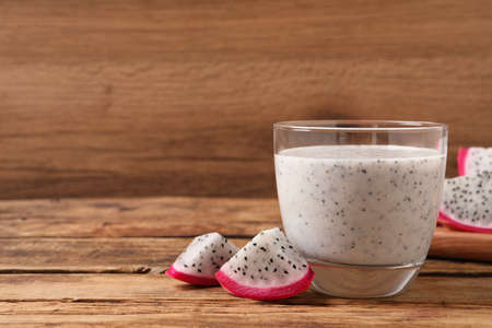 Glass of tasty pitahaya smoothie and fresh fruit on wooden table, space for textの写真素材