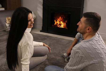 Lovely couple spending time together near fireplace at homeの写真素材