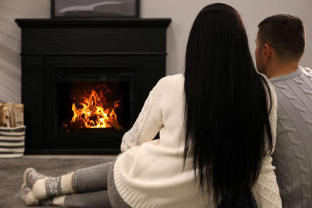 Lovely couple spending time together near fireplace at homeの写真素材