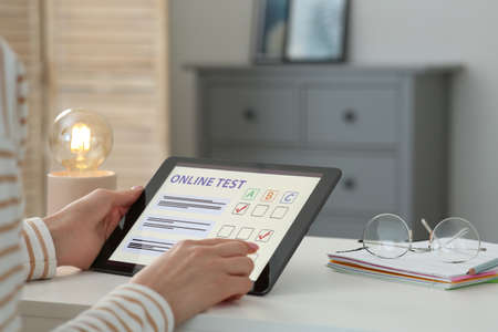 Woman taking online test on tablet at desk indoors, closeupの写真素材