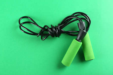 Skipping rope on green background, top view. sports equipment