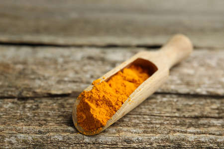 Scoop with saffron powder on wooden table, closeup