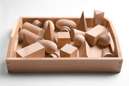 Set of wooden geometrical objects in box isolated on white. Montessori toy