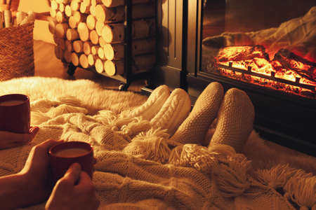 Couple in knitted socks near fireplace at home, closeupの写真素材
