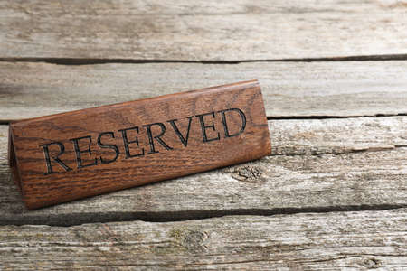 Elegant sign RESERVED on wooden surface, space for text. Table setting elementの写真素材