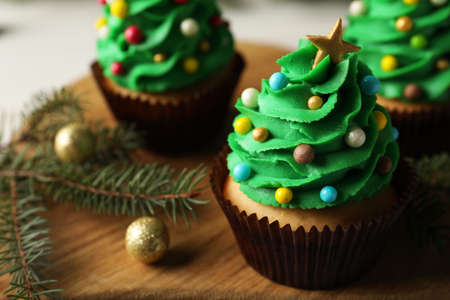Tasty Christmas cupcakes on wooden board, closeup. Space for textの写真素材