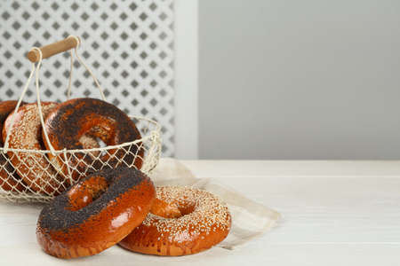 Many delicious fresh bagels on white wooden table, space for textの写真素材