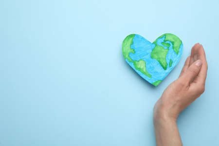 Woman and heart shaped model of planet on light blue background, top view with space for text. earth dayの写真素材