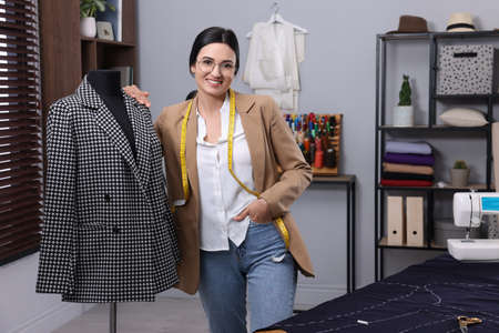 Dressmaker near mannequin with jacket in workshop