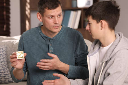 Father talking with his teenage son about contraception at home. sex education conceptの写真素材