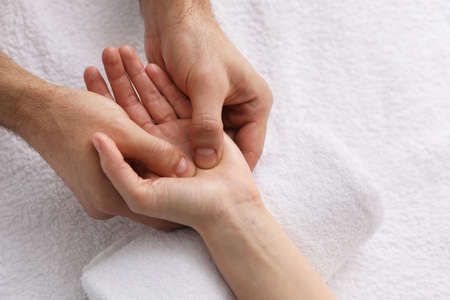 Woman hand receiving massage on soft towel, above view