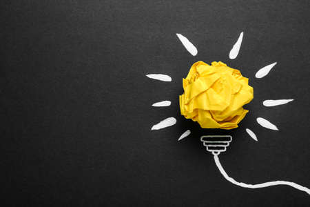 Composition with crumpled paper ball and drawing of lamp bulb on blackboard, top view. idea concept