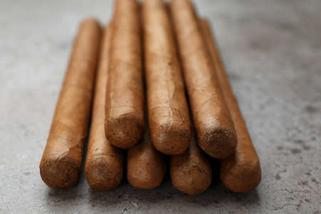 Many expensive cigars on gray table, closeup