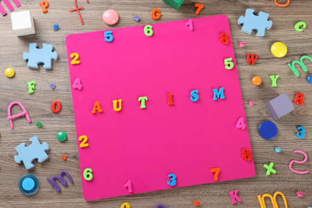 Flat lay composition with word Autism and colorful letters on wooden tableの写真素材