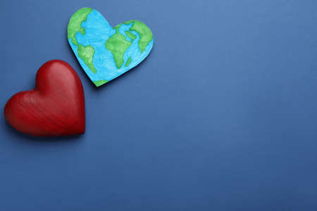 Model of planet and red heart on blue background, flat lay with space for text. earth day
