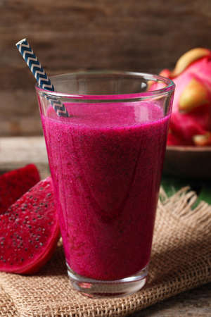 Glass of tasty pitahaya smoothie and fresh fruits on wooden tableの写真素材