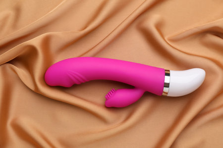 Pink vibrator on golden silk fabric, top view. sex toyの写真素材
