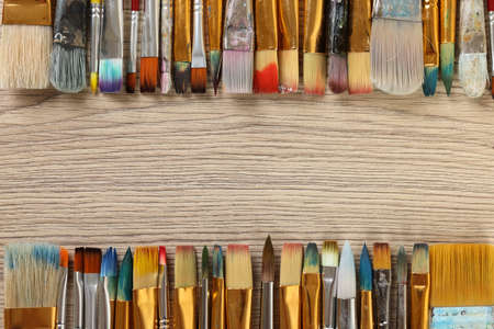 Set of different paintbrushes on wooden table, flat lay. Space for textの写真素材